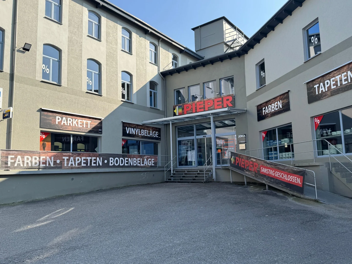 Eingang des Betriebs Pieper Maler- und Fußbodenbedarf in Herford mit Schildern für Farben, Tapeten und Bodenbeläge.